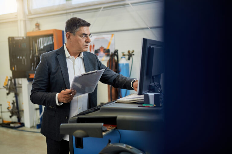 Mid adult manager working on a computer in auto repair shop